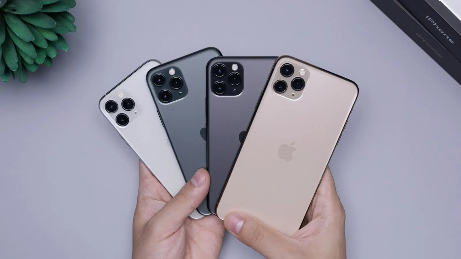 Four used iPhones held in two hands, in different finishes