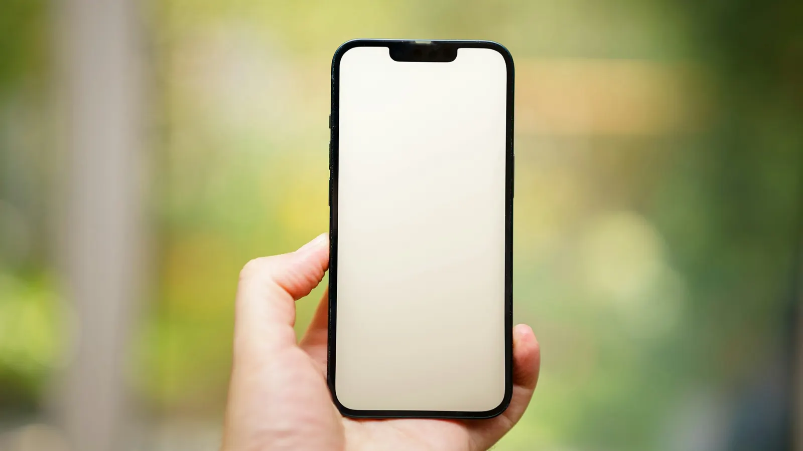 A hand holding out a smartphone against a green background
